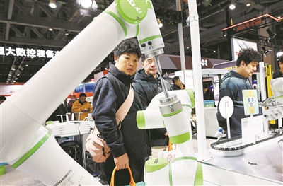 2025上海国际机床展上,参观者在一个进行作业演示的双臂协同机器人前驻足观看。 新华社记者 方喆摄